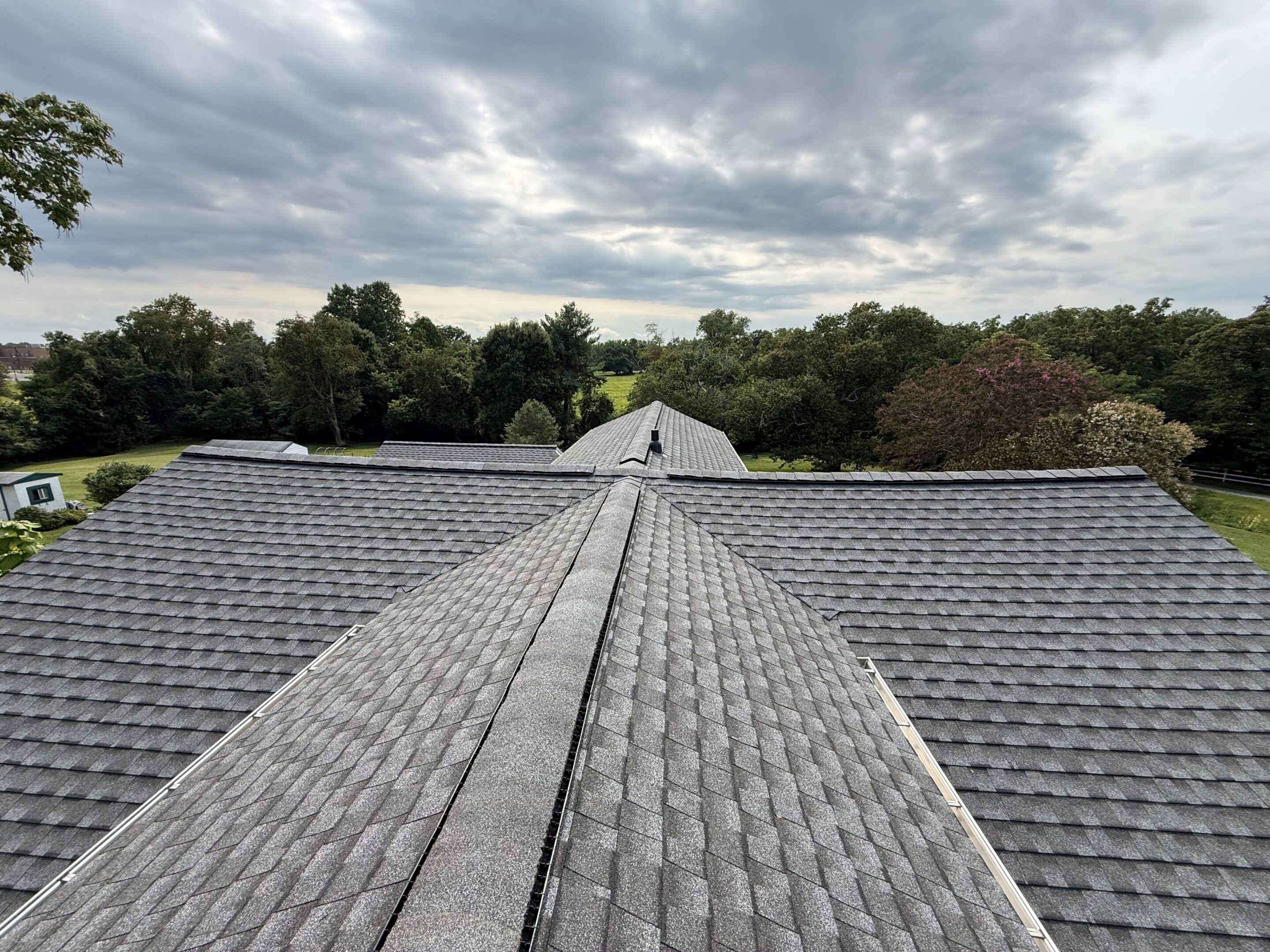 Gray shingled roof with cloudy sky backdrop.